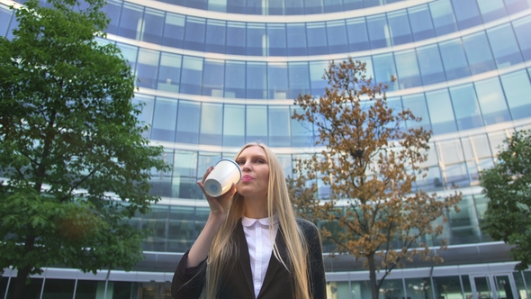 Stylish Business Woman with Coffee on Street. From Below of Serious Blond Executive Woman in Suit