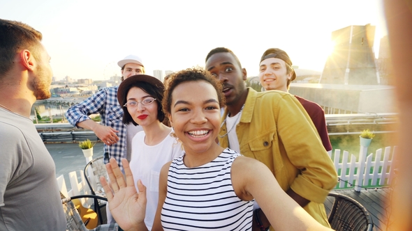 Cheerful African American Girl Is Taking Selfie Adjusting Camera Then Calling Her Friends, Posing