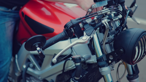 Biker Activates the Ignition of the Motorcycle on the Side of the Highway.