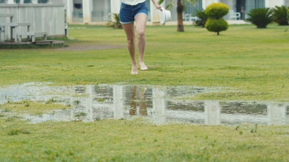 The Female Naked Legs Running Through the Puddle at Lawn