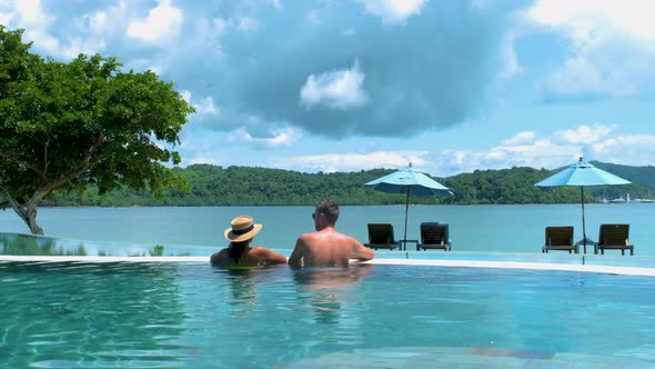 Couple European Man and Asian Woman in Infinity Pool in Thailand Looking Out Over the Ocean Luxury