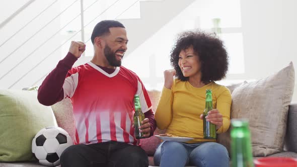 Couple cheering while watching sports on TV at home