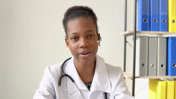 Young African American Woman Doctor Having Chat or Consultation on Laptop Looking Directly