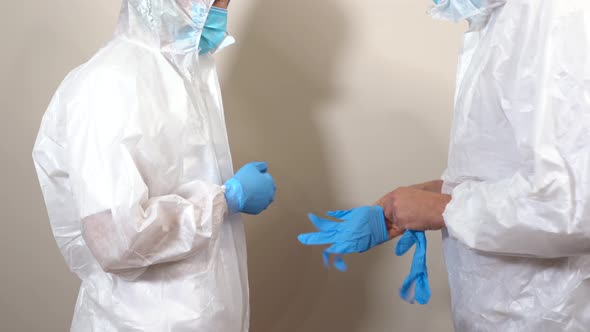 female doctor in ppe suit instructing colleague to put on gloves
