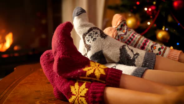 Footage of Family Wearing Woolen Socks Warming By the Fire in Fireplace in Living Room Decorated