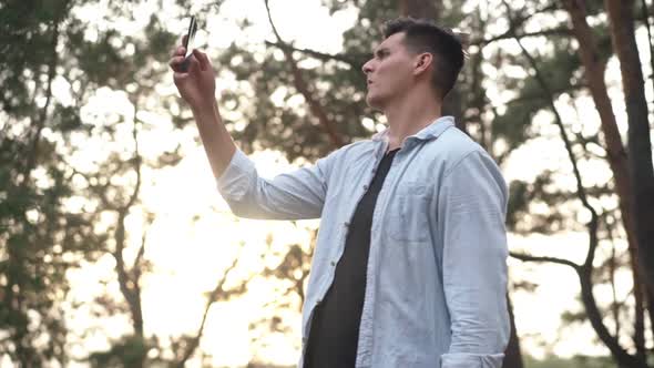 Worried Anxious Man Searching Mobile Network Raising Smartphone Standing in Forest