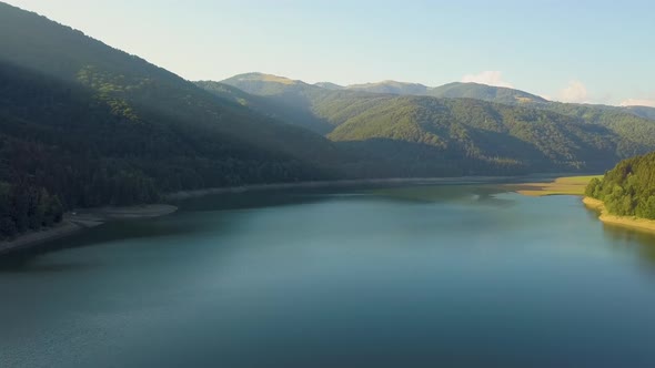 Aerial View of Big Lake with Clear Blue Water Between High Mountain Hills Covered with Dense