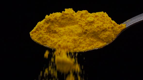 Turmeric Yellow Falling From the Iron Spoon, Black Background Studio, Slow Motion