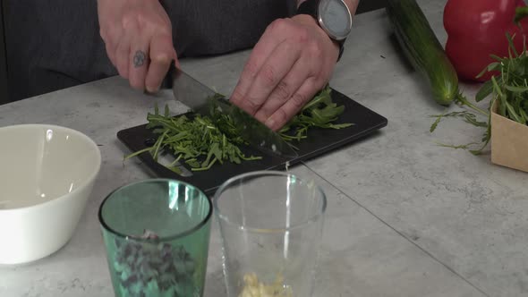 Fresh arugula chopped on small cutting board, other ingredients nearby