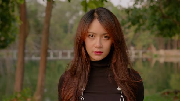 Thai Young Woman Slowly Looks Up Into the Camera in the Park at Sunset
