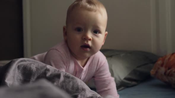 A Baby Girl in Pink Romper Suit on a Messy Bed
