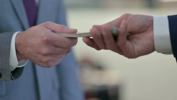 Close Up of Businessman Giving Dollars To Another Businessman