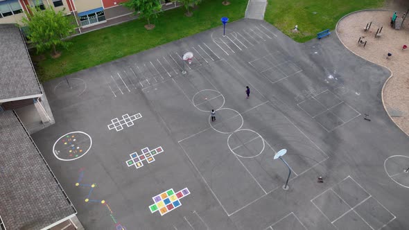 Aerial shot of kids shooting hoops at an elementary school after hours.