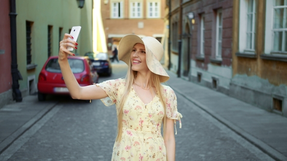 Woman Taking Selfie on Street. Cheerful Young Woman Walking on Old European Town Street and Taking