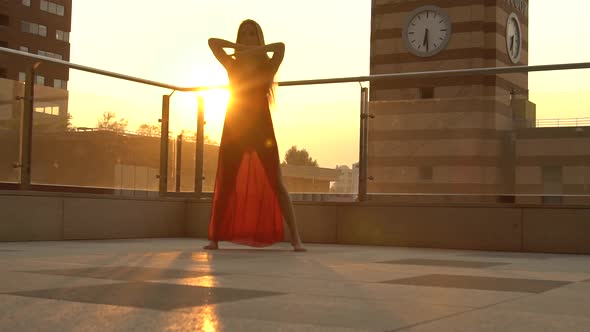 Beautiful Young Girl Dancing on the Street of a Modern City in the Sunset Light