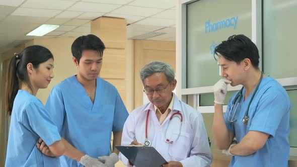 Team of asian doctor nurse consult together on patients file at hospital.