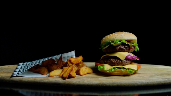 of Delicious Burger with Double Cheese and French Fries. Black Background