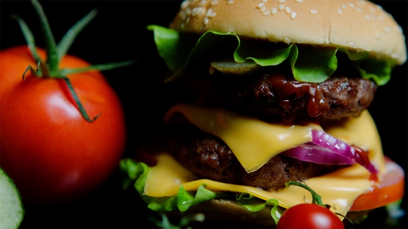 of Fresh Vegetables and Tasty Burger with Cheese and Beef Cutlets on the Black Background