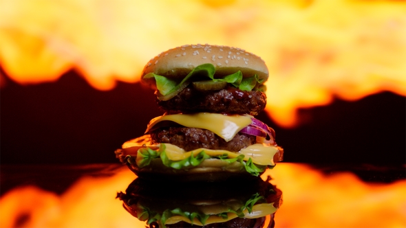 Burger on the Black Mirror Surface The Flame of Grill on the Background Out of Focus