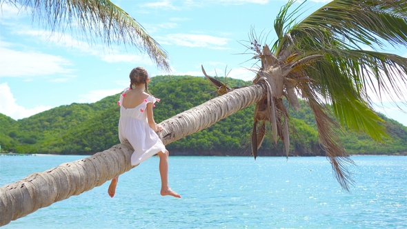 Adorable Little Girl at Tropical Beach on Palm Tree During Summer Vacation