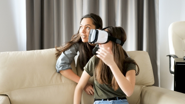 Two Sisters Having Fun with a Virtual Reality Headset