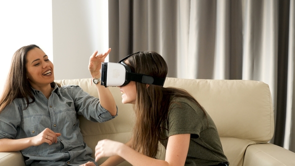 Teenage Girl with a VR Headset on Next To Her Bigger Sister