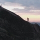 Aerial Shot of Two Friends of Tourists Climb a High Rock at Sunset. - VideoHive Item for Sale
