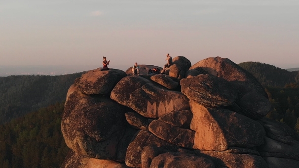 Epic Drone Shot of Friends Enjoy the Sunset Sitting on Top of a High Mountain in the Siberian Stolby
