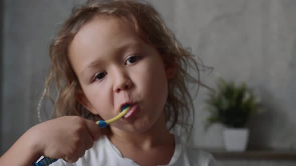 Portrait of Little Girl is Intensively Brushing Her Teeth in Bathroom