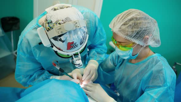 Patient receiving plastic operation. Surgeon and his assistant performing cosmetic surgery