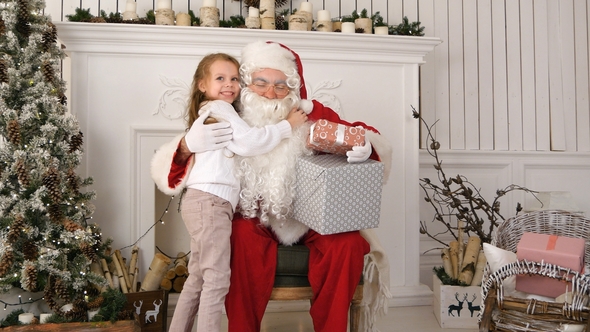 Santa Claus Holding Presents and Hugging a Little Cute Girl