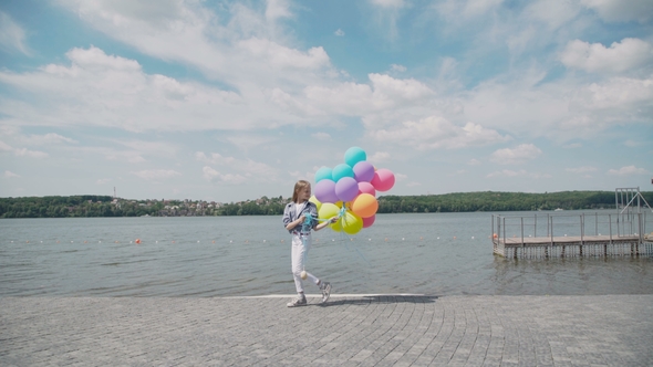 Pretty Girl Walks on the River Bay with Colourful Balloons and Looks on Water