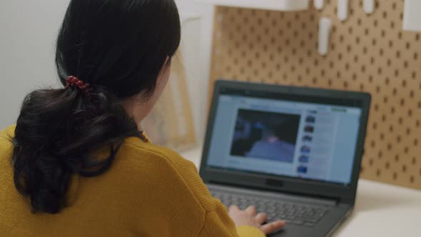 Asian woman using a laptop searching on the internet shopping online during COVID-19 pandemic.