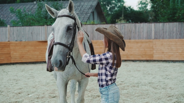 Young Happy Girl Smiling and Caressing Her Pretty White Horse on the Area