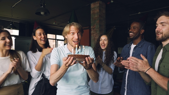 Bearded Guy with Expressive Face Is Making Wish and Blowing Candles on Birthday Cake While His