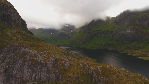 Aerial View of Clouds Moving Over Steep Mountain Peaks and Lake at Midnight Sun, Lofoten, Norway