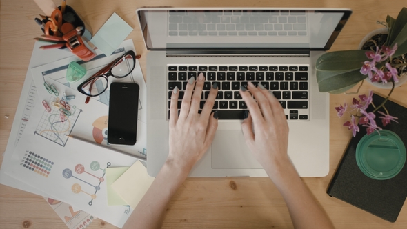 Young Journalist Is Typing an Article on a Laptop Top View