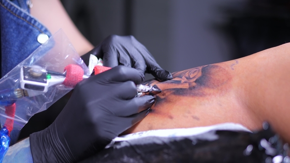 Tattoo Artist Demonstrates Process of Getting Black Tattoo with Paint and Machine. Woman Works in