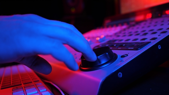 Sound Engineer Rotates the Scroll Wheel on Mixing Console in a Professional Recording Studio