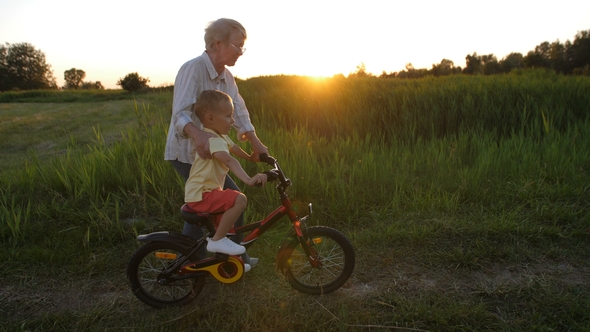 Toddler Boy Riding Bicycle with Grandmother's Help