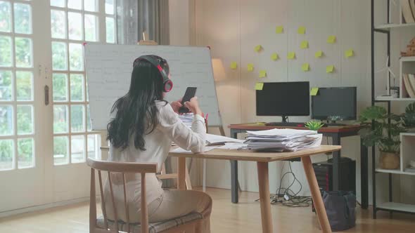 Back View Of Asian Woman Wearing Headphones To Listen To Music Before Dancing After Working