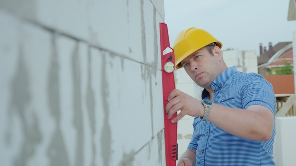 The Architect in the Yellow Helmet Using the Level Checks the Accuracy of the Construction of Walls