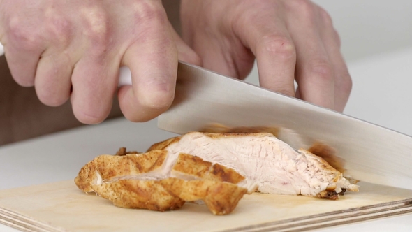 Cooks' Hands Cut the Baked Meat Into Pieces in