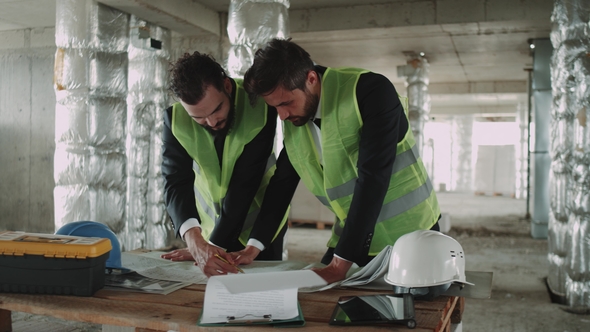 Team of Engineer Men Looking Through the Construction Building Map