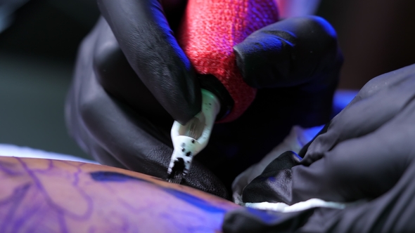 View of Tattoo Artist Demonstrates the Process of Getting Black Skull Tattoo with Paint