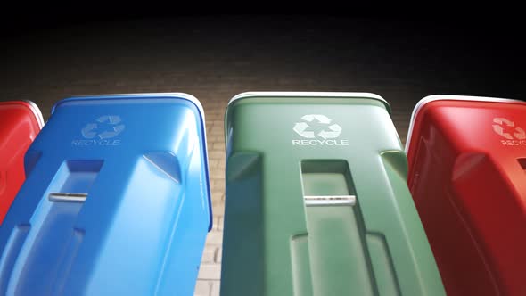 Colorful plastic garbage bins stacked in a row against a brick wall in a loop.