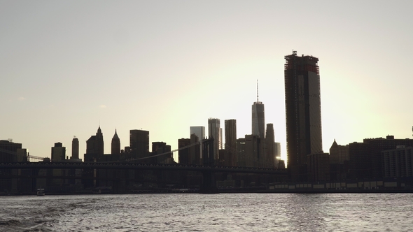 A Sunset Sunflare Shines Through Lower Manhattan Skyline and Brooklyn Bridge in New York, United