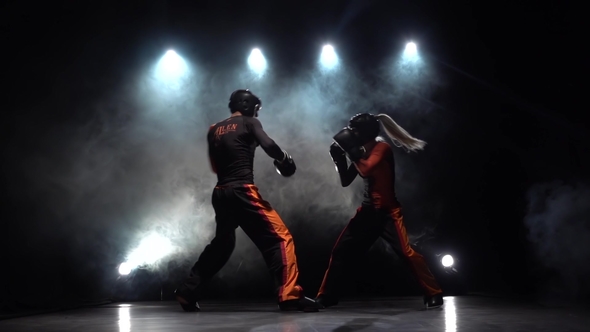 Woman Is Kicking a Guy with Their Sparring Kickboxing. Smoke Background. Silhouette.