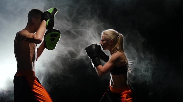 Guy Trainer and the Girl on the Boxing Paws Working Off the Straight Punches of the Kickboxing