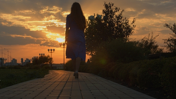 Girl Walking Away Through Park at the Sunset